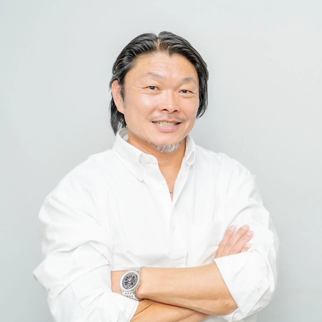 縁屋のスタッフ。白いシャツで腕を組み、笑顔でこちらを見ている